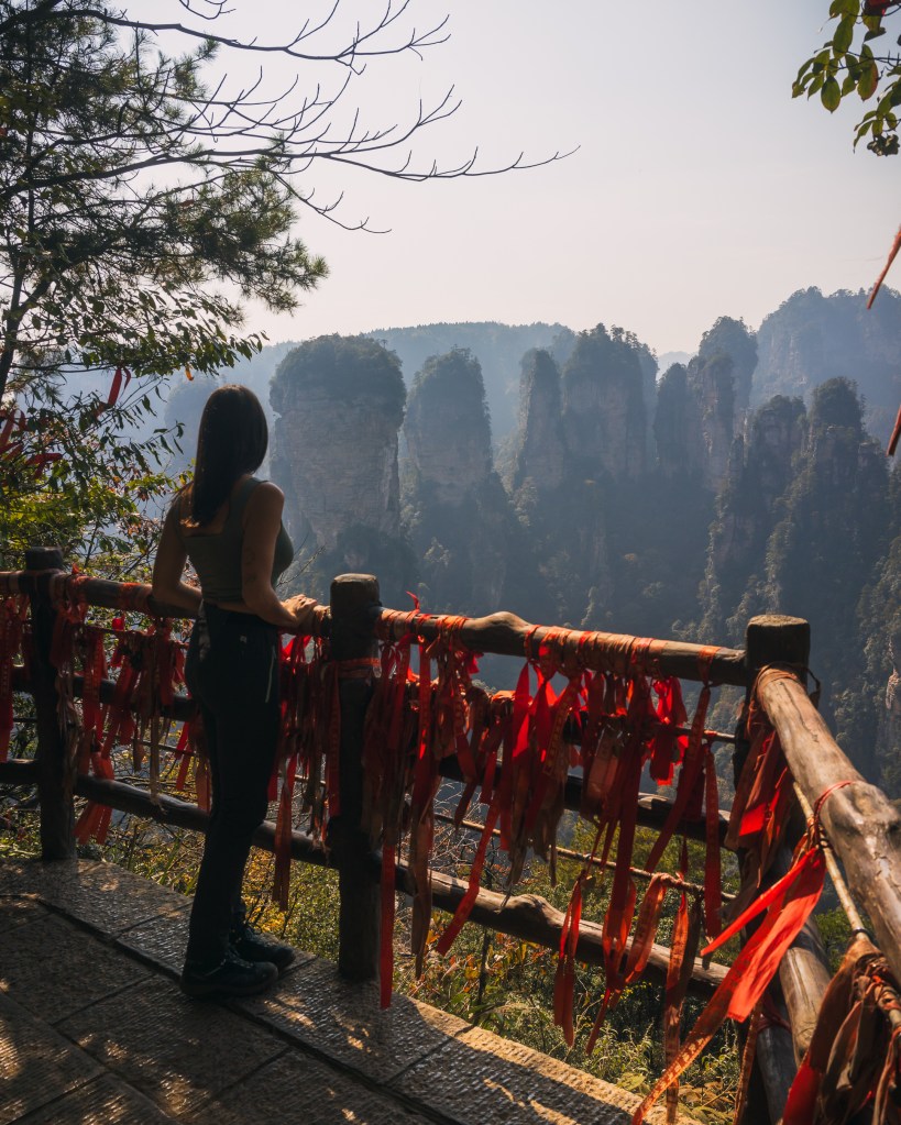 Chica admira el paisaje de zhangjiajie desde un balcón lleno de lazos rojos